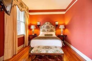 a bedroom with a bed with orange walls and two lamps at Charming Durham Studio Steps Away from Duke in Durham