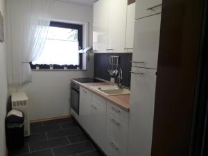 a kitchen with white cabinets and a sink and a window at Urlaub und Wellness im Fichtelgebirge in Warmensteinach +11 photos