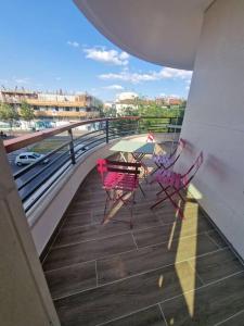 a balcony with two red chairs and an umbrella at Magnifique Appartement Paris La Défense in Colombes