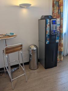 a soda machine sitting next to a table and a stool at Hotel des Voyageurs in Millau