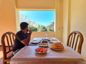 a man sitting at a table with food on it at Runnel View in Masinagudi