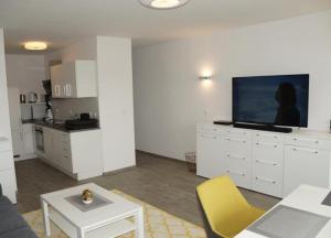 un salon avec une télévision et une cuisine dans l'établissement WoogeBella - Traumblick auf die Nordsee, à Wangerooge 8 autres photos