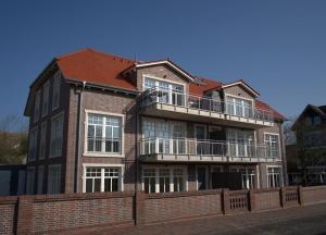 a large brick building with a balcony on a street at Miss Evans macht blau in Wangerooge