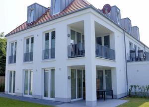 ヴァンガーオーゲにあるStrandlust - Anspruchsvolle Ferienwohnungの白い家で、バルコニーとテーブルが前にあります。
