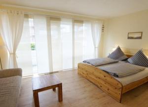 ein Schlafzimmer mit einem Holzbett und einem großen Fenster in der Unterkunft Lüttjer Strandloper in Wangerooge