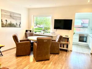 ein Wohnzimmer mit Tisch und Stühlen und einem Fernseher in der Unterkunft Meike 2 - Ebenerdige Wohnung mit Terrasse und kleinem Garten in Wangerooge
