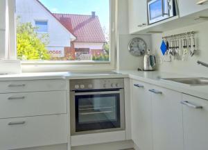 eine weiße Küche mit einem Herd und einem Fenster in der Unterkunft Meike 2 - Ebenerdige Wohnung mit Terrasse und kleinem Garten in Wangerooge