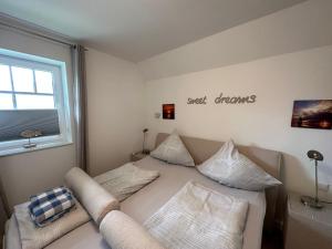 ein Schlafzimmer mit einem Bett mit Kissen und einem Fenster in der Unterkunft Skipper - Apartment mit Stil an den Dünen in Wangerooge