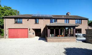a brick house with a red garage and a red door at Yewtree House in Penrith