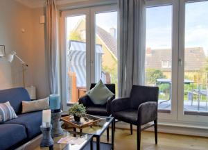 - un salon avec un canapé bleu et deux chaises dans l'établissement Strandvogt - wunderschöne Ferienwohnung mit Parkettboden und Sonnenbalkon, à Wangerooge