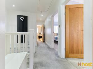 a hallway with a door and a room with a bed at Host Liverpool - Greasby Luxury Home, Near Golf & Beach in Greasby