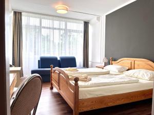 two beds in a room with two chairs and a window at Landhotel Harz in Thale
