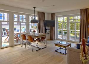 a living room with a table and chairs and a couch at Linnenboom - lichtdurchflutete Neubauwohnung für gehobene Ansprüche in Wangerooge