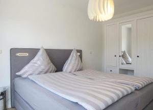 a bed with white sheets and pillows in a bedroom at Linnenboom - lichtdurchflutete Neubauwohnung für gehobene Ansprüche in Wangerooge