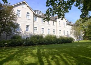 a large white building with a green lawn in front of it at WangerRose - Familienwohnung für Groß und Klein und Hundefreunde in Wangerooge