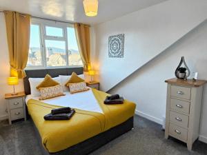 a bedroom with a yellow bed and a window at Squirrel Lodge in Keswick +30 photos