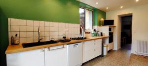 una cocina con armarios blancos y paredes verdes en logis Ozanie, en Javrezac