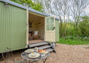a green shed with a table in front of it at The Orchards Retreat Shepherds Hut in Saint James