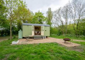 a green shed with a grill in a yard at The Orchards Retreat Shepherds Hut in Saint James