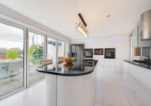 a white kitchen with a large island in the middle at Swallows Return in Camrose