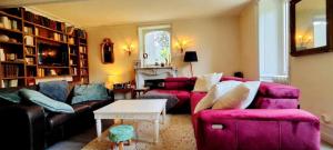 ein Wohnzimmer mit einem rosa Sofa und einem Tisch in der Unterkunft logis Ozanie in Javrezac