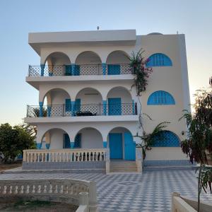 ein Gebäude mit blauen Türen und einem Balkon in der Unterkunft Dar El Ferdaous in Zarzis
