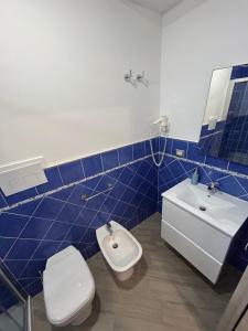W wyłożonej niebieskimi kafelkami łazience znajduje się toaleta i umywalka. w obiekcie Da Nonna Nina Casa Vacanza w mieście Acciaroli