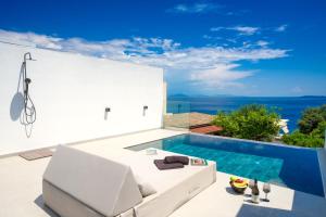 a villa with a swimming pool and a white couch at Akrogiali Apartments in Barbati