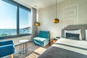 a bedroom with a bed and a chair and a window at Hotel Delfin in Rovinj