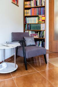 a chair and a table and a book shelf with books at Guest house Barbara in Nerežišća