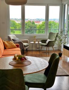 uma sala de estar com uma mesa, cadeiras e janelas em Park & Play em Banja Luka