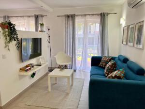 uma sala de estar com um sofá azul e uma televisão em The Old Village Studio Vilamoura em Vilamoura