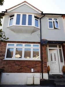 a white house with windows and a door at Feel at Home in Elmers End