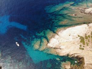 an overhead view of a boat in the water near a cliff at Eco Village Baia Delle Ginestre in Teulada