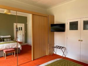 1 dormitorio con 1 cama y TV en la pared en Blackburn Villa B&B en Ayr