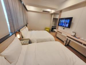 a hotel room with two beds and a flat screen tv at Gucheng International Hotel 