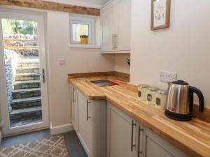 cocina con armarios blancos y encimera de madera en Rose Cottage, en Buxton