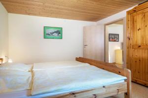 1 dormitorio con cama y techo de madera en Tobelbach, en Weiler-Simmerberg