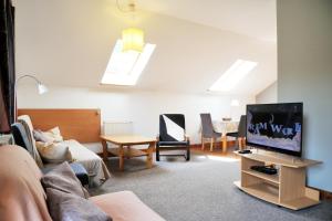 a living room with a couch and a tv at Duży apartament w Karpaczu, cisza, parking, balkon lub taras, zieleń, plac zabaw, sklep 5min in Karpacz