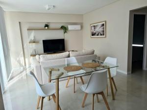 a living room with a glass table and white chairs at Departamento premium para 3 personas in Puerto Madryn