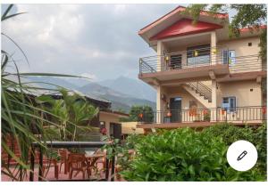 a house with a balcony with a view of the mountains at Riva dreams in Dharamshala