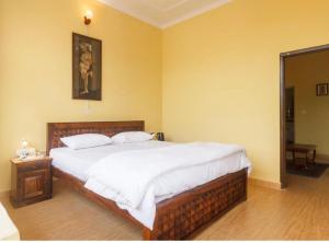a bedroom with a large bed with white sheets at Riva dreams in Dharamshala