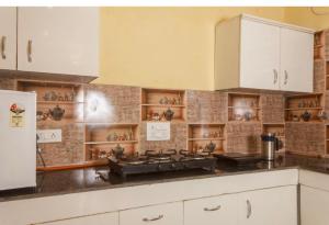 a kitchen with white cabinets and a stove at Riva dreams in Dharamshala