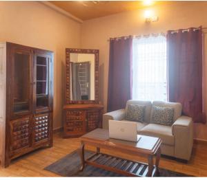 a living room with a couch and a table with a laptop at Riva dreams in Dharamshala