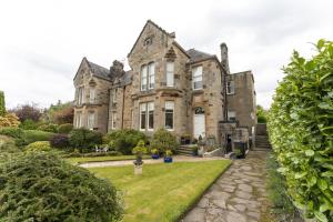 una antigua casa de piedra con un jardín delante de ella en The Lindsay House, en Stirling