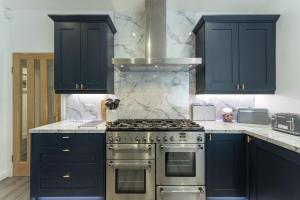a kitchen with blue cabinets and a stainless steel stove at The Lindsay House in Stirling