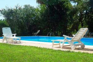 2 Stühle, ein Tisch und ein Pool in der Unterkunft Grande villa con piscina privata in Maruggio