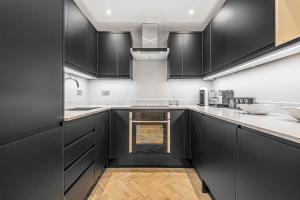 a kitchen with black cabinets and wooden floors at Flat 5 in London