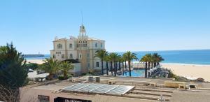 a building on the beach with a pool and the ocean at Vistamar Apartments in Portimão