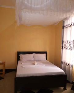 1 dormitorio con 1 cama con sábanas blancas y ventanas en MHALO BEACH LODGE, 